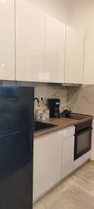 a kitchen with white cabinets and a black refrigerator at La Maisonette, Florina Center in Florina