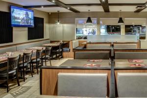 un restaurant avec des tables et des chaises et une télévision à écran plat dans l'établissement Hôtel-Motel Normandin Alma, à Alma