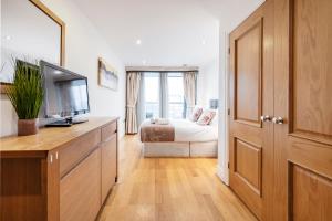 a bedroom with a bed and a television and a dresser at Modern Paddington Station 2 Bedroom Apartment in London