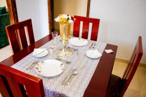 una mesa con platos y un jarrón de flores. en Lavish Haven Home, en Bungoma