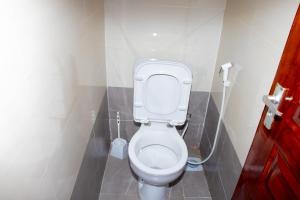a white toilet in a bathroom with a red door at Lavish Haven Home in Bungoma