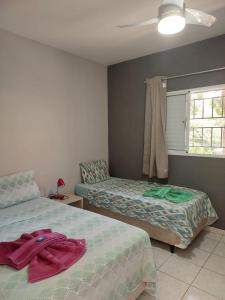 a bedroom with two beds and a window at Flat Pé de Mamão in Campinas