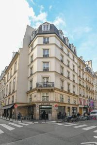 ein hohes weißes Gebäude in einer Stadtstraße mit einer Straße in der Unterkunft Paris, Opéra 2D...pour un séjour magique in Paris