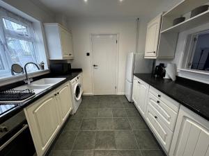 a kitchen with white cabinets and a sink and a dishwasher at Station house in Ramsgate