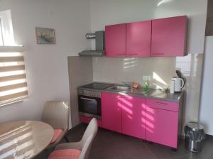 una cucina rosa con lavandino e piano cottura di Apartments Blaža a Podstrana
