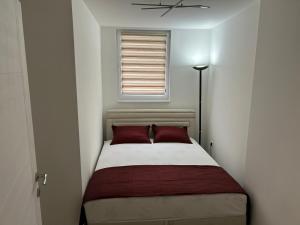 a small bedroom with a bed with two red pillows at Apartman Magus in Tuzla