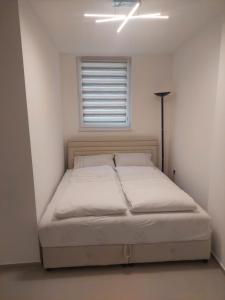 a bed in a white room with a window at Apartman Magus in Tuzla