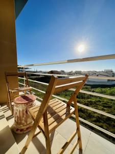 a wooden bench sitting on a balcony looking out at a train at Onda Beach House in Cortegaça