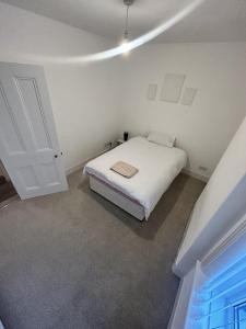 a white bedroom with a bed and a door at Canvas House in Carlisle