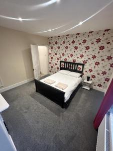 a bedroom with a large bed with floral wallpaper at Canvas House in Carlisle