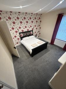 1 dormitorio con 1 cama con flores en la pared en Canvas House en Carlisle