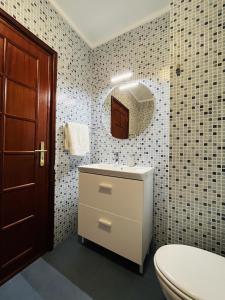 uma casa de banho com um WC, um lavatório e um espelho. em Onda Beach House em Cortegaça