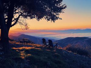 two chairs and a picnic table on a hill with the sunset at 100 Mile View-Fire Pit, Romantic, Peaceful, Private in Crestline