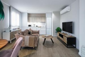sala de estar con sofá, TV y mesa en La Terraza de Lulú Little Apartments en Cádiz
