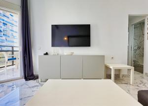 um quarto branco com uma televisão numa parede branca em SKOL 424 Stunning One-bedroom apartment with sea views em Marbella