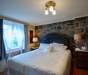 a bedroom with a large bed and a stone wall at Manoir Sainte Genevieve in Quebec City