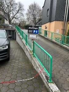 un coche estacionado junto a una valla verde con una señal de estacionamiento en Hotel zum Postwagen en Gevelsberg