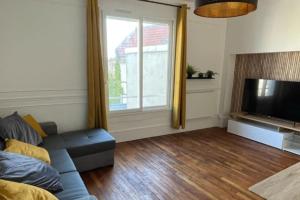 ein Wohnzimmer mit Sofa und Fernseher in der Unterkunft Le 131 in Reims