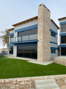 a building with a lawn in front of it at DieStrandwolf Sea View Self Catering in Hentiesbaai