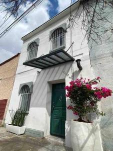 ein weißes Gebäude mit grüner Tür und Blumen in der Unterkunft PV. Studio 3 ppl, centro, tiny house, 1 habitacion in Chihuahua