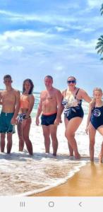 a group of people walking on the beach at RM Holiday Home in Hikkaduwa