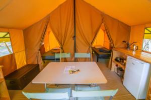 pokój ze stołem i krzesłami w namiocie w obiekcie Camping Onlycamp Le Val Joyeux w mieście Château-la-Vallière