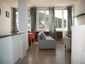 een woonkamer met een bank, een stoel en ramen bij El Tarter-Vacances Pirinenca in El Tarter
