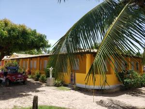 una casa amarilla con una palmera delante de ella en Pousada Grão de Areia Beira Mar en Mangue Sêco