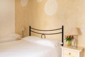 Duas camas num quarto com dois candeeiros e flores em Palazzo De Luca by Apulia Hospitality em Fasano