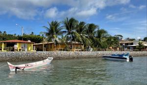 two boats sitting in the water next to a wall at Pousada Grão de Areia Beira Mar in Mangue Sêco