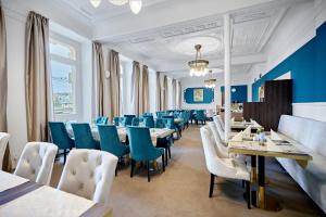 a dining room with tables and blue chairs at Hotel Maxim in Mariánské Lázně