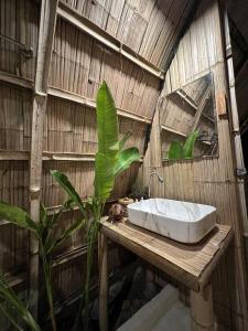łazienka z umywalką i rośliną na drewnianym stole w obiekcie The Por Beach w mieście Ko Por