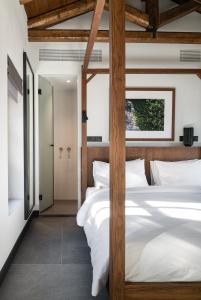 1 Schlafzimmer mit 2 weißen Betten mit Holzpfosten in der Unterkunft Unedo All Seasons Hotel in Palaios Panteleimonas
