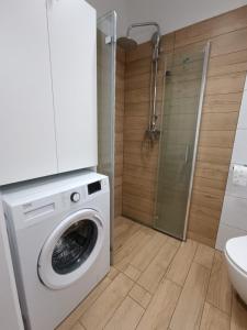 a white washing machine in a bathroom with a shower at Apartament Sienkiewicza in Starachowice