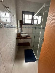 een badkamer met een wastafel en een glazen douche bij Chalés Solana localizados 50 metros do mar in Garopaba
