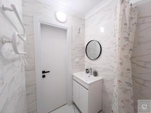 a white bathroom with a sink and a mirror at Renthouse Apartments City Gates #4 in Chişinău