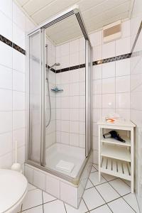a white bathroom with a shower and a sink at Hotel Poggenstool in Neuharlingersiel
