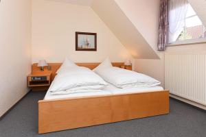 Un dormitorio con una cama con almohadas blancas y una ventana en Hotel Poggenstool, en Neuharlingersiel