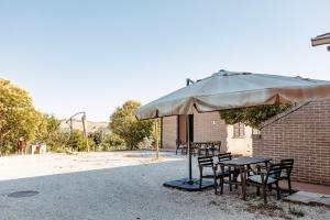 a table and chairs under a large umbrella at Agricola La Casetta in Montefiore dellʼAso