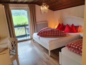 een slaapkamer met 2 bedden met rode kussens en een raam bij Boutique Hotel Alpenhof in Sankt Martin am Tennengebirge