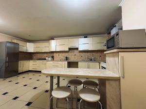 a kitchen with white cabinets and a counter with stools at VerhoVilla in Verkhovyna