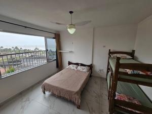 a bedroom with two bunk beds and a large window at Apartamento em Peruíbe (Centro) in Peruíbe