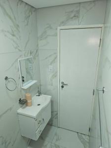 a white bathroom with a sink and a mirror at Apartamento em Peruíbe (Centro) in Peruíbe +11 photos