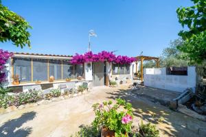 Una casa con flores moradas en el frente. en La caseta dels iaios, en Masdenverge