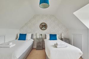 two beds with blue pillows in a bedroom at Oakey Cottage in Bourton on the Water