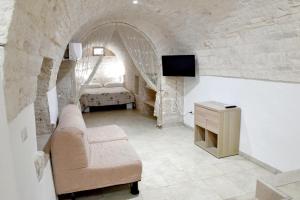 ein Wohnzimmer mit einem Sofa, einem TV und einem Bett in der Unterkunft Agape fra i Trulli Dimora Ciclamino in Alberobello