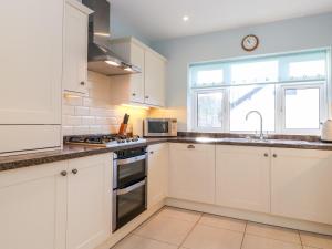 een keuken met witte kasten, een wastafel en een raam bij Rainbow End in Ambleside