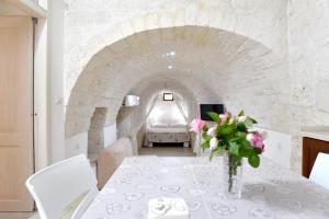 ein weißes Esszimmer mit einem weißen Tisch und Blumen in der Unterkunft Agape fra i Trulli Dimora Ciclamino in Alberobello