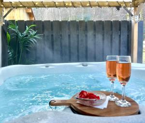 two glasses of beer and a bowl of strawberries next to a swimming pool at Bluebell Cottage with Hot Tub in Ballachulish
