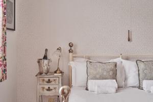 a bedroom with a bed with white pillows and a night stand at Oakey Cottage in Bourton on the Water